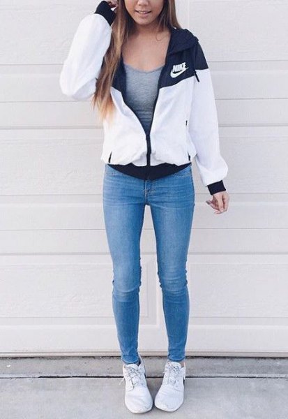 white windbreaker with a gray, form-fitting tank top and blue skinny jeans