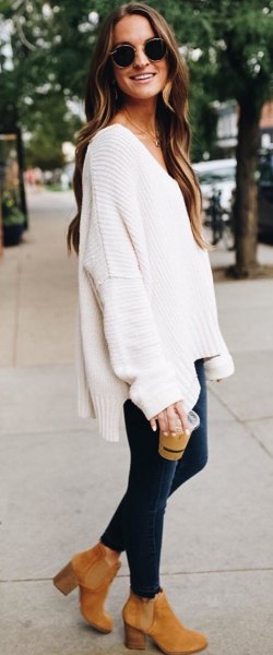 white, chunky V-neck sweater with dark blue skinny jeans and camel boots