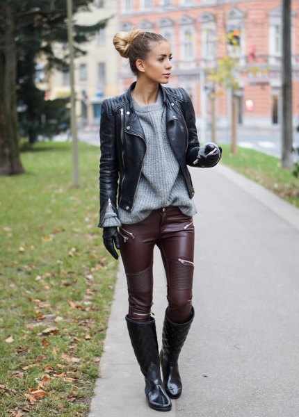 black biker jacket with gray, ribbed sweater and leather gaiters