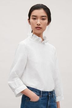 white mock-neck blouse with blue skinny jeans