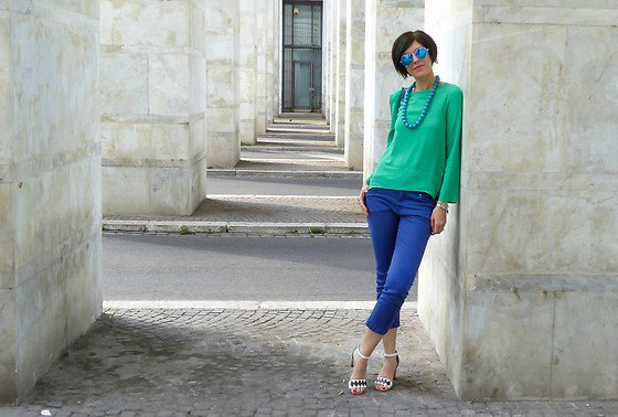 Bright emerald green long-sleeved top with a relaxed fit and short-cut jeans in royal blue