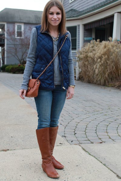 blue quilted vest with gray long-sleeved top and brown knee-high boots