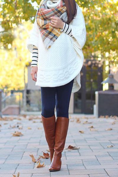 white tunic sweater with wide sleeves and knee-high boots made of brown leather