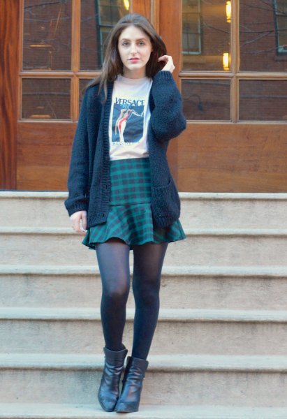black knit sweater with white printed t-shirt and dark blue plaid skirt