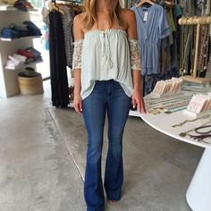 white from the shoulder pleated blouse with flared blue jeans
