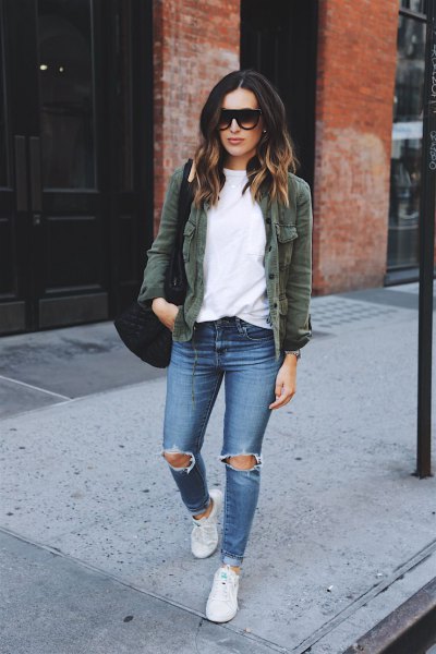 olive jacket with white sweater and ripped blue jeans