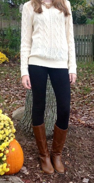 white knit sweater with black leggings and knee-high boots in brown leather