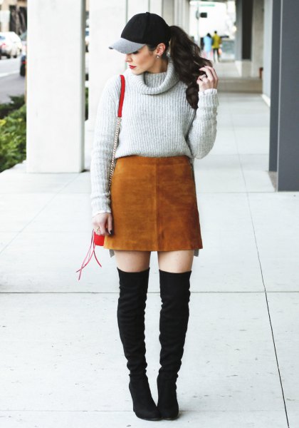 gray sweater with cabbage neck with brown suede skirt and black thigh boots in the thigh