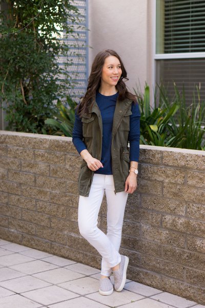 brown work vest with navy blue long sleeve top and white jeans