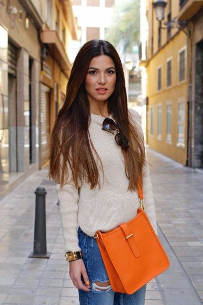 white fitted sweater with crew neck with blue boyfriends and orange handbag