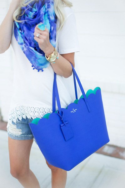 white crochet tee with denim shorts and royal blue handbag
