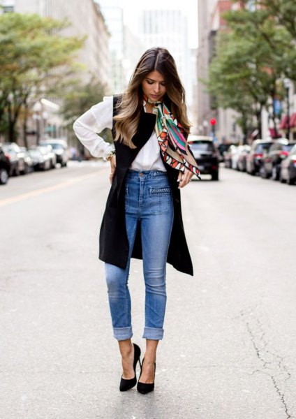 white button up shirt with black long vest and blue cuffed high waist jeans