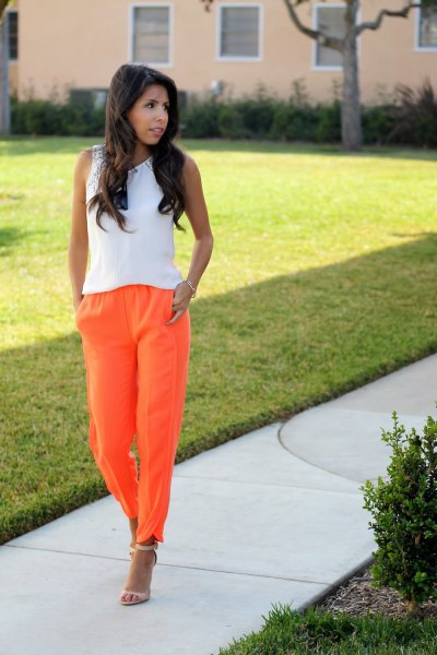 white sleeveless top with orange pull on jeans