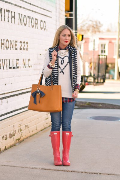 white embroidered sweater with blue jeans and orange rain boots in the knee