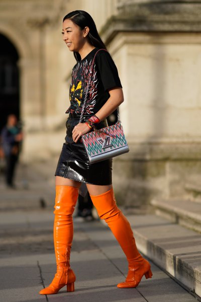 black tee and leather skirt with high boots in orange leather