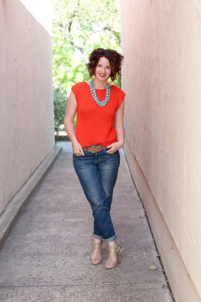 orange sleeveless blouse with cuffed jeans and brown belt