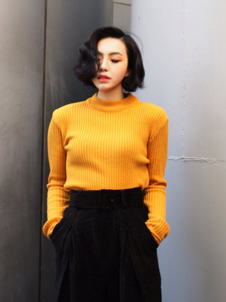 ribbed yellow sweater with black wide legged trousers