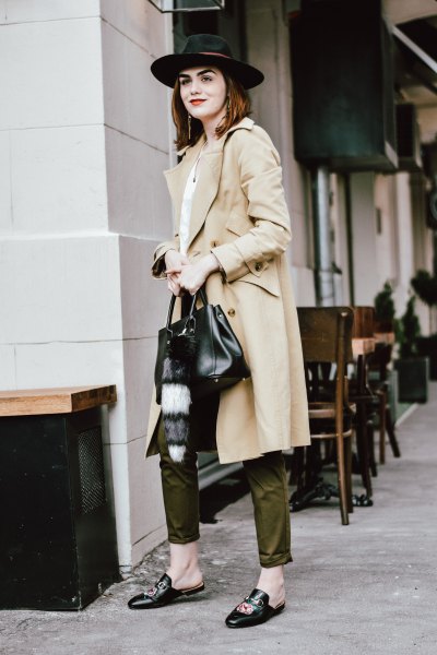 long beige trench coat with green pants and felt hat