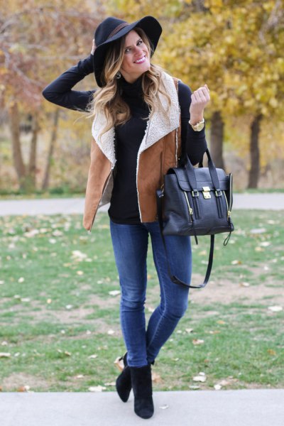 black mock neck sweater with shearling vest of camel and blue jeans