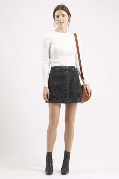 white form fitting ribbed sweater with black button front denim mini skirt