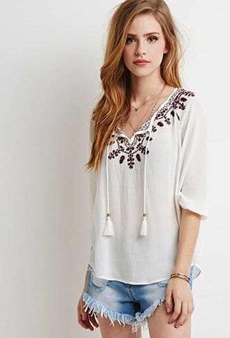 white peasant top with tassel details with blue fringed mini denim shorts