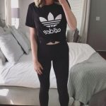 Black Adidas T-shirt with black leggings and all white sneakers .