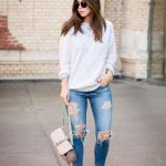 With loose sweatshirt, distressed jeans and small bag .